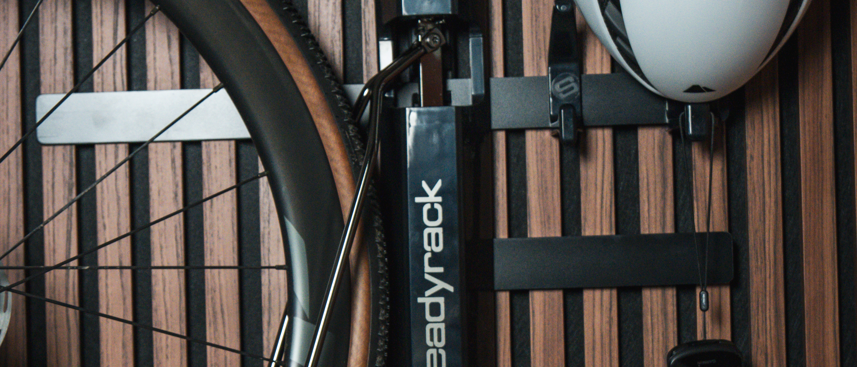 A small snippet of a bicycle wheel and helmet on a wooden background.