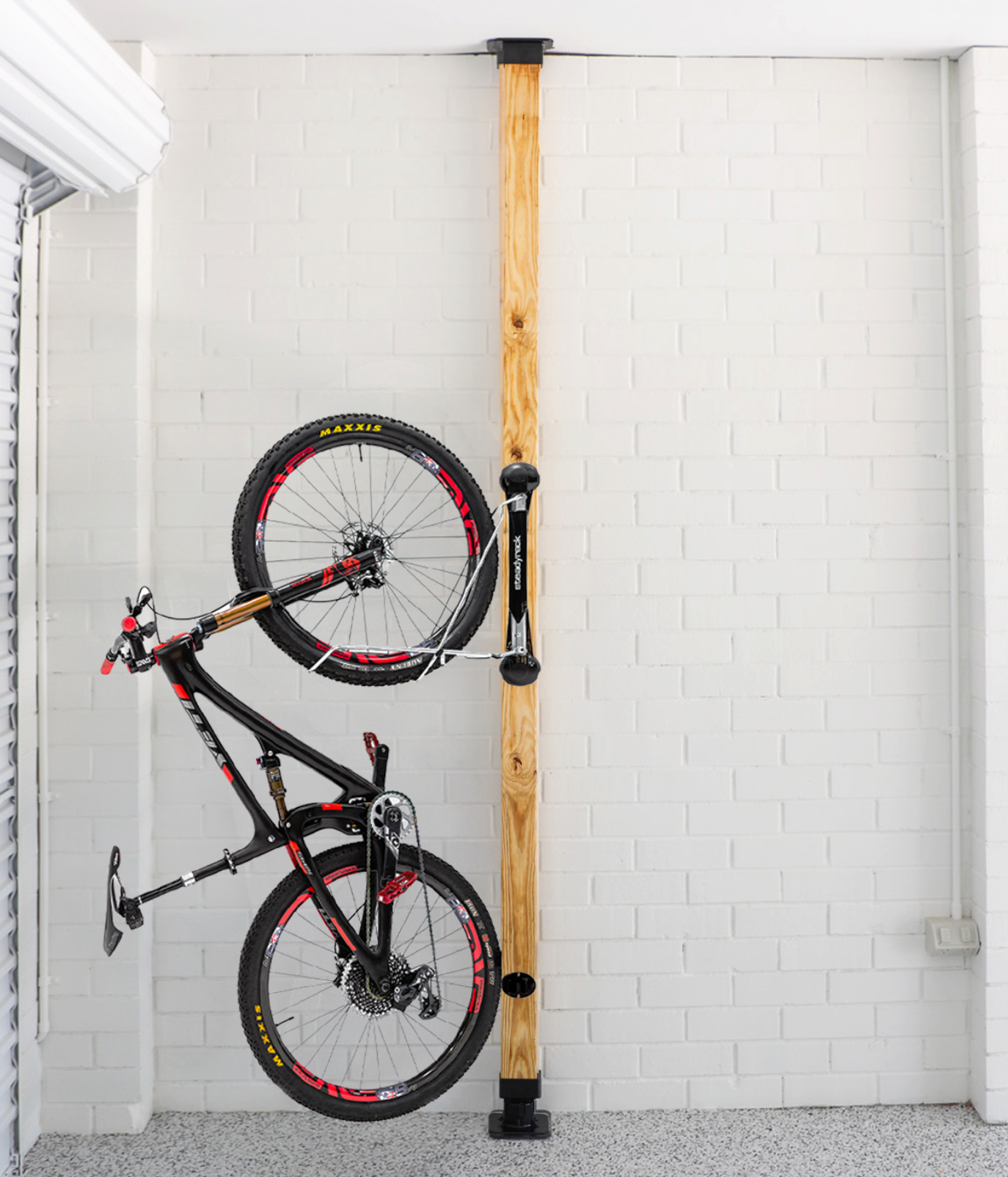 Bicycle installed on a vertical wooden post in a garage setting.