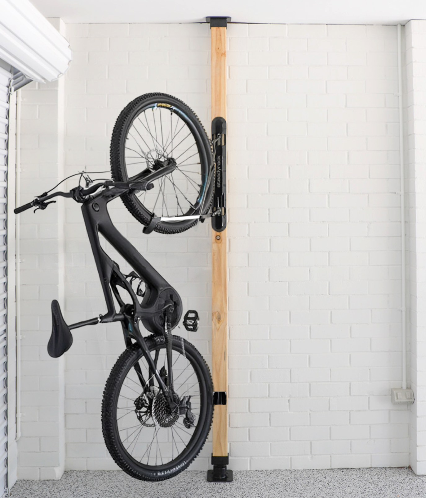 Black bike in a wall mount rack white white brick background