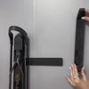 A person sliding a black helmet hooking onto a black metal bracket. 