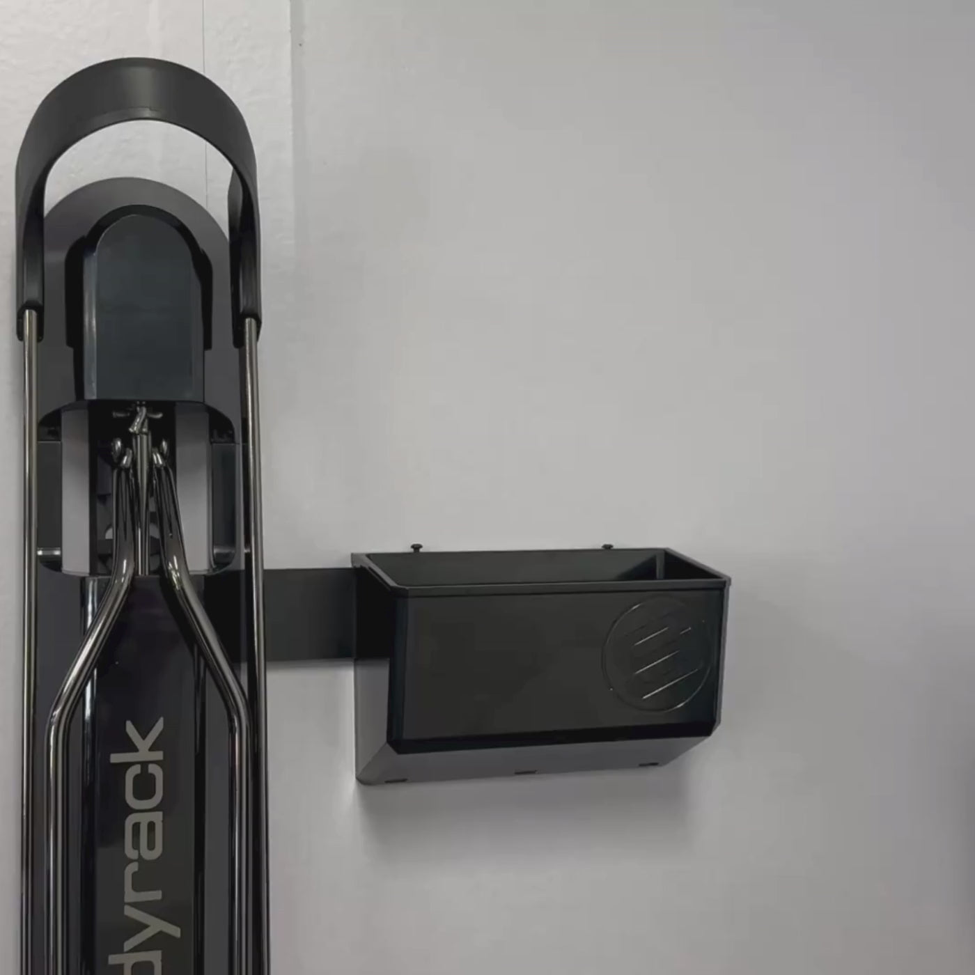 A person placing an electric bike charger into a GearMate Small SteadyBin attached with a bracket to a bike rack. 